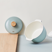 The 20cm Happycall Zium ceramic nonstick induction pot in a sage green finish, shown with its matching lid, light wood knob, and dual side handles.