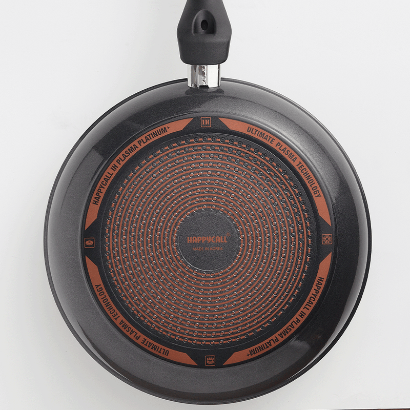Bottom View of Happycall Plasma Titanium Frypan: The bottom of the Happycall Plasma Titanium Frypan, showcasing the unique circular pattern with branding and technology labels. The base is designed for induction compatibility.

