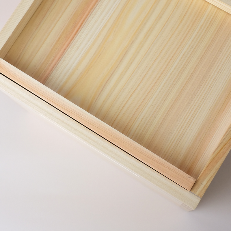 A close-up of the corner of the Hinoki rice box, detailing the wooden construction and the track for the sliding lid.