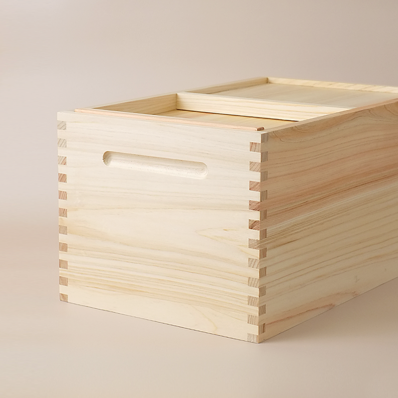 The Hinoki Cypress Wooden Rice Storage Box (5kg), highlighting its natural wood grain, traditional finger-joint construction, and recessed handle.
