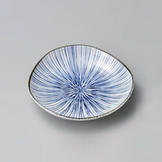 A studio photo of the Ichiku Mino Yaki Fine Ten Grass Side Plate, showcasing its irregular shape and hand-painted blue lines radiating from the centre.
