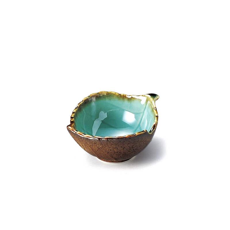 A Japanese side bowl shaped like a leaf, showing its vibrant emerald green interior and contrasting rough, dark brown exterior.