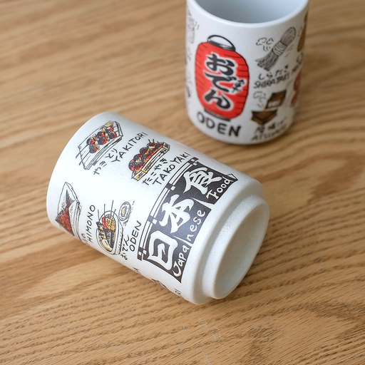 A cylindrical Japanese teacup (yunomi) featuring playful illustrations of popular Japanese dishes like Yakitori, Oden, and Takoyaki, with labels in English and Japanese.