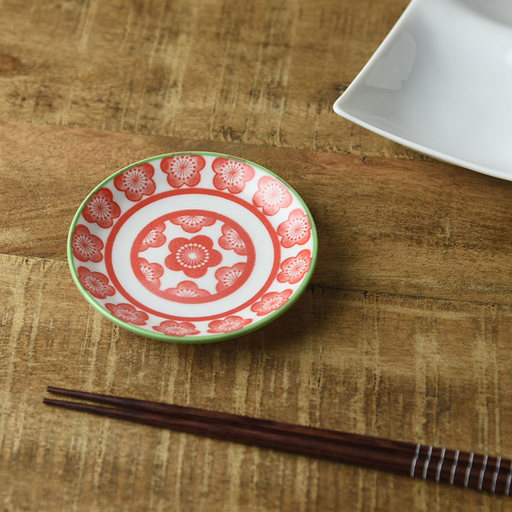 Miyama Japonesque Pink Blossom mini plate with red coral plum blossom pattern and green rim, shown on a wooden surface beside chopsticks

