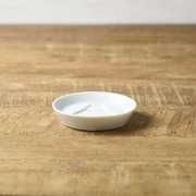An angled view of the white Kageasobi Mount Fuji sauce plate on a wooden table.

