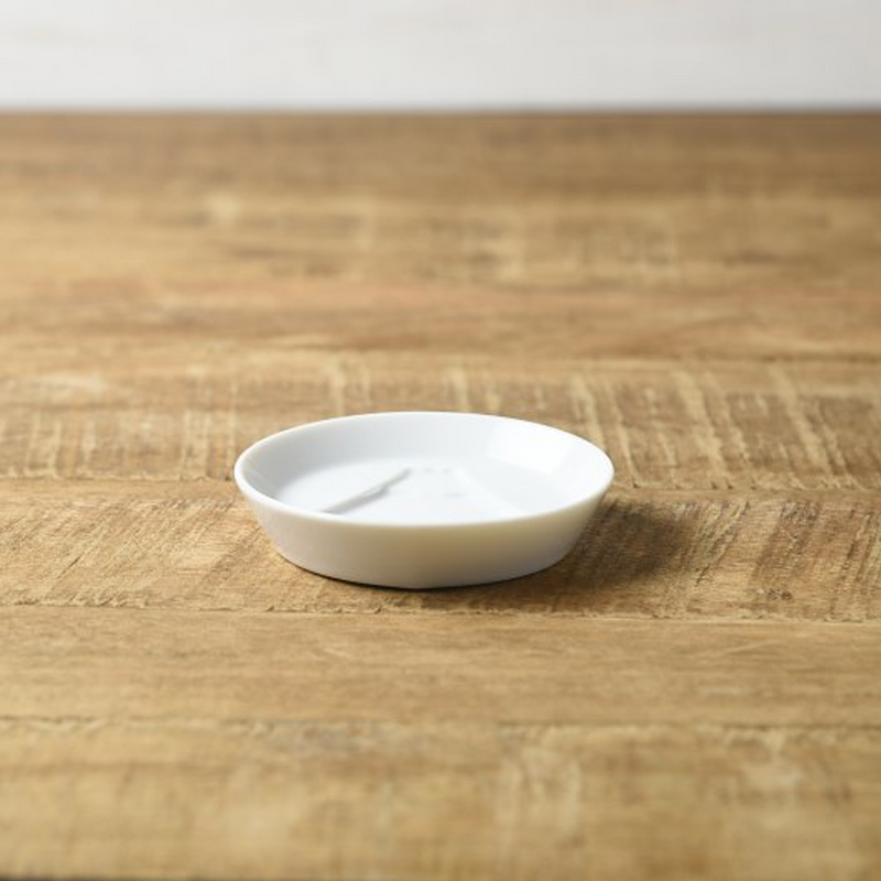 An angled view of the white Kageasobi Mount Fuji sauce plate on a wooden table.

