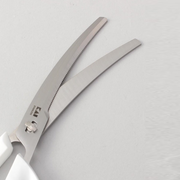 A detailed close-up of the blades on the Kai kitchen scissors, showing their curved shape and the fine serrations on one edge.
