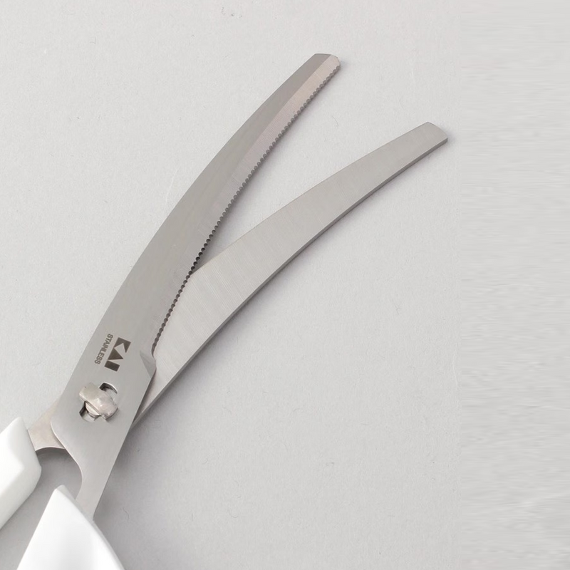 A detailed close-up of the blades on the Kai kitchen scissors, showing their curved shape and the fine serrations on one edge.

