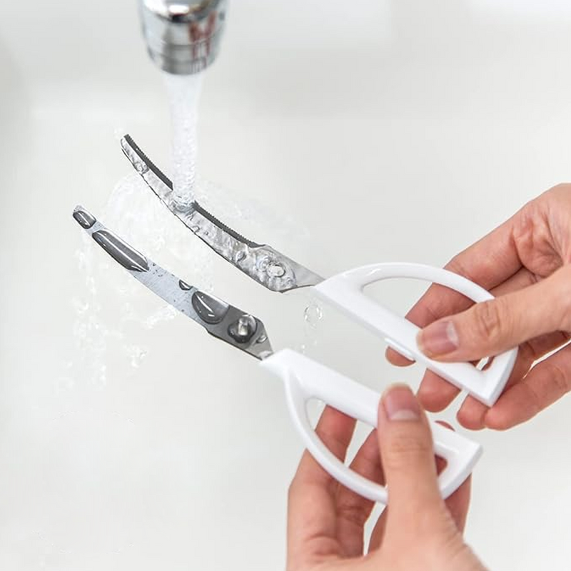 A demonstration of the Kai kitchen scissors' detachable design, showing the two blades separated for easy and thorough cleaning under a tap.
