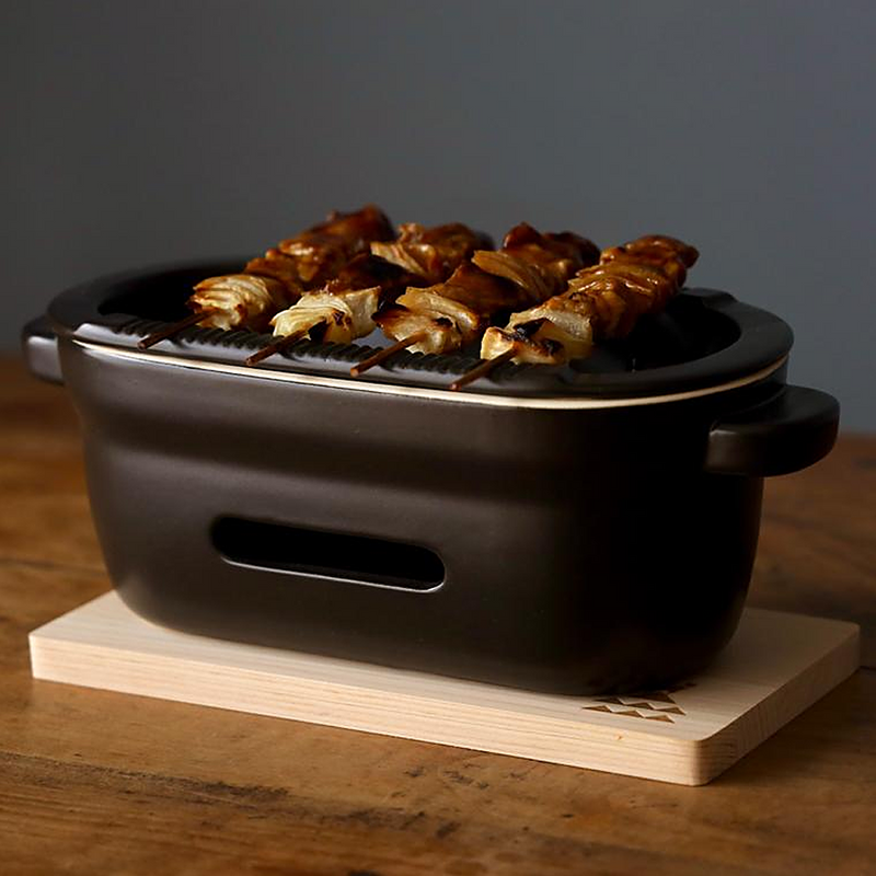 A close-up of chicken and onion yakitori skewers grilling on the Kamoshika Douguten konro grill.

