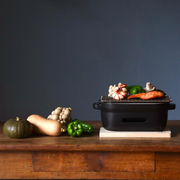 The Kamoshika Douguten konro grill on a wooden table with fresh ingredients like salmon, shrimp, mushrooms, and squash ready to be cooked.

