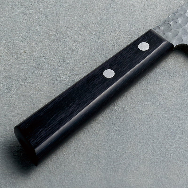 A detailed close-up of the Kaneyoshi knife's black laminated reinforced wood handle and stainless steel rivets.

A detailed close-up of the Kaneyoshi knife's black laminated reinforced wood handle and stainless steel rivets.

