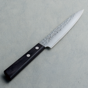 A full view of a Kaneyoshi Hammered VG10 Japanese knife, showcasing the hammered blade finish and black wood handle.


