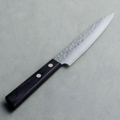 A full view of a Kaneyoshi Hammered VG10 Japanese knife, showcasing the hammered blade finish and black wood handle.


