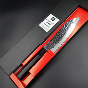 The Kasumi Kuro Santoku knife presented in its elegant black and red gift box.

