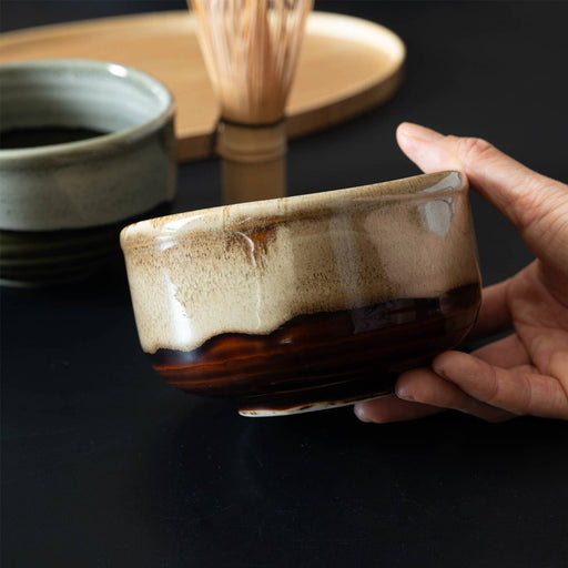 Hand holding the Keisai Miyajima 450ml matcha bowl, pale glaze flowing over deep brown