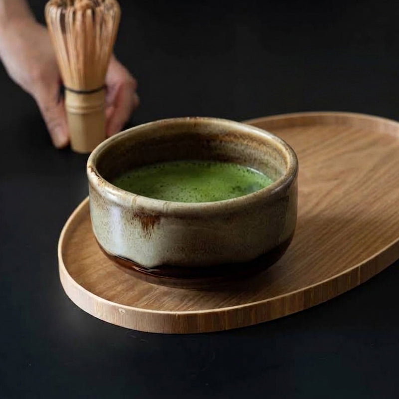 Keisai Miyajima matcha bowl with whisked matcha and a bamboo whisk on a wooden tray