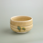 A studio shot of the Kiseto Yellow Seto matcha bowl, showing its warm yellow glaze, signature green accents, and fine crackle finish.