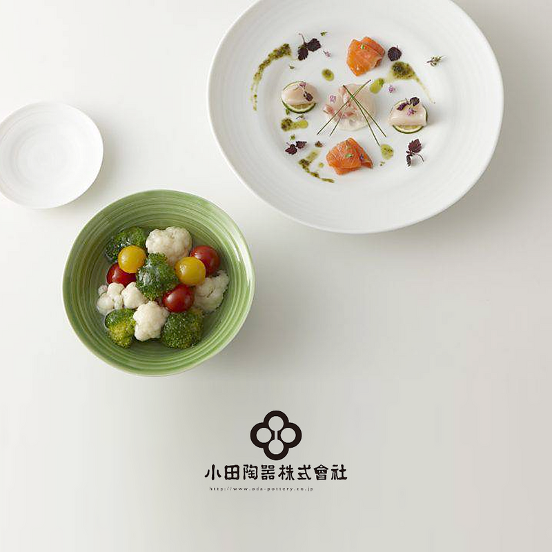 A lifestyle image showing the Kushime Dinner Plate styled with a fine dining dish of scallops and salmon, alongside other tableware.

