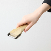 A hand holding the Kyoto Katsugu peeler against a white background to show its size and the comfortable grip of its wooden handle. 