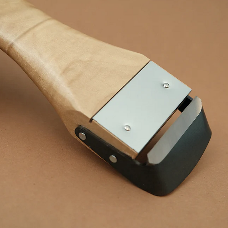 A detailed close-up of the Kyoto Katsugu peeler's head, showing the high-carbon steel blade and its attachment to the wooden handle. 