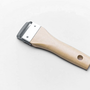 A detailed close-up of the Kyoto Katsugu Forged Peeler, showing the sharp high-carbon steel blade and traditional wooden handle.

