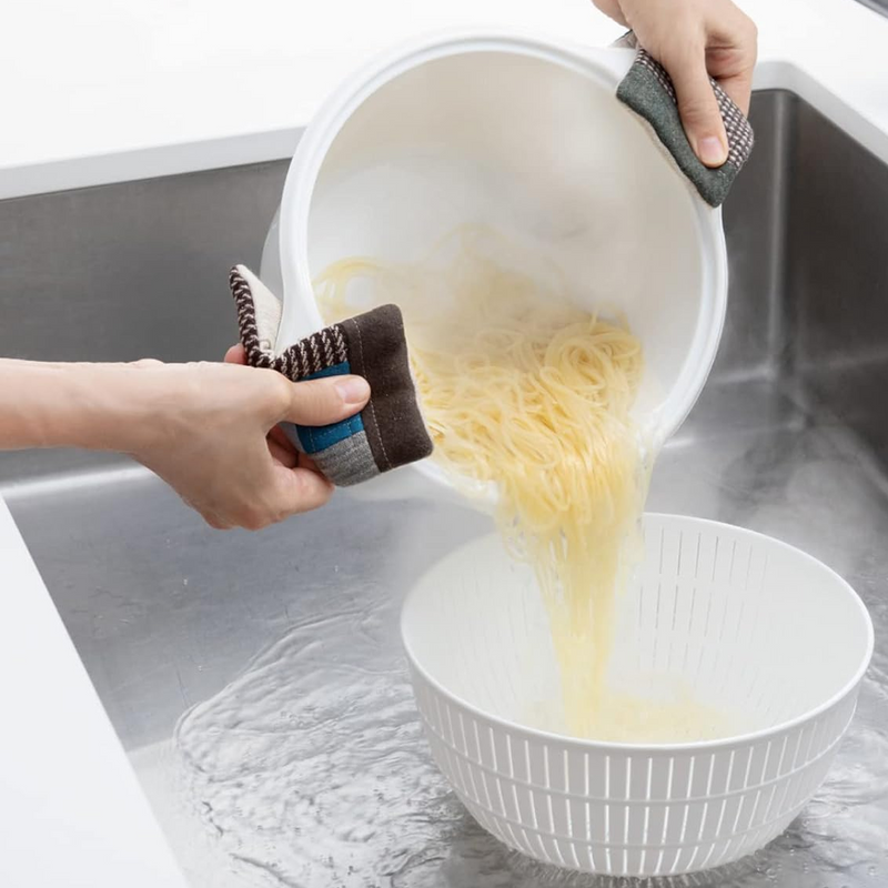 Draining freshly cooked pasta from a pot into the large white Like-it colander in a kitchen sink.