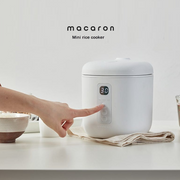 Close-up of a user setting the timer on the LocknLock Macaron Mini Rice Cooker, showcasing its digital controls and compact design.