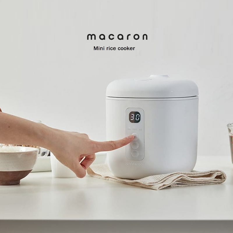 Close-up of a user setting the timer on the LocknLock Macaron Mini Rice Cooker, showcasing its digital controls and compact design.
