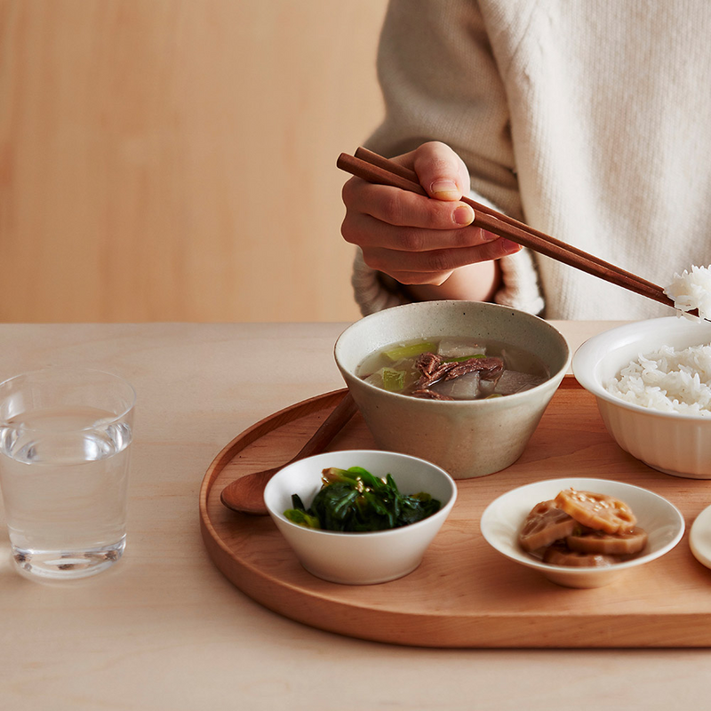 A person enjoying a healthy meal of rice, soup, and vegetables prepared using the LocknLock Macaron Mini Rice Cooker, illustrating its practicality for single servings.