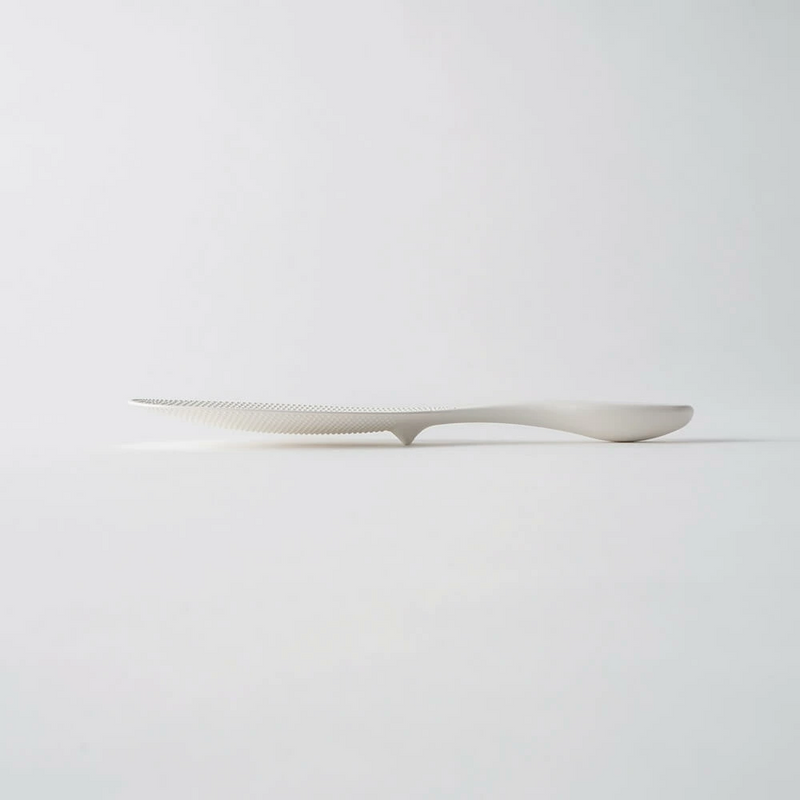 An elegant side profile of the Marna rice scoop, showing its thin paddle and curved handle design.