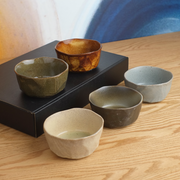 A lifestyle photo of the Mino Yaki 'Kuradashi' 5-Piece Japanese Bowl Gift Set, showing the five unique rustic bowls arranged on a wooden table with their black gift box.


Sources






