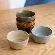 The complete 5-piece Mino Yaki Kuradashi Japanese bowl set displayed on a wooden table, with three bowls stacked and two in the foreground to show the variety of unique glazes.