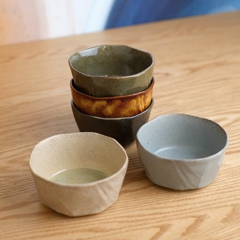The complete 5-piece Mino Yaki Kuradashi Japanese bowl set displayed on a wooden table, with three bowls stacked and two in the foreground to show the variety of unique glazes.