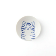 A top-down view of the Shichita Mino Yaki Cat Dora side bowl, showing the inquisitive, striped cat illustration on a white porcelain surface.