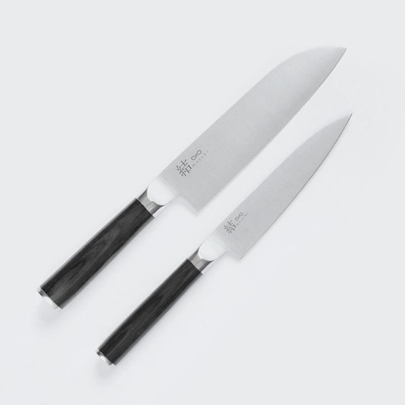 A Santoku knife and a Petty knife from the Mitsuboshi Musubi series, featuring stainless steel blades with subtle branding and dark Pakkawood handles, displayed on a light background.