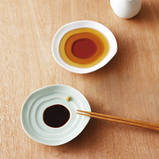 The Miyama Haas Soy Sauce Plate shown in use, holding a pool of soy sauce that highlights the plate's unique rippled shape.