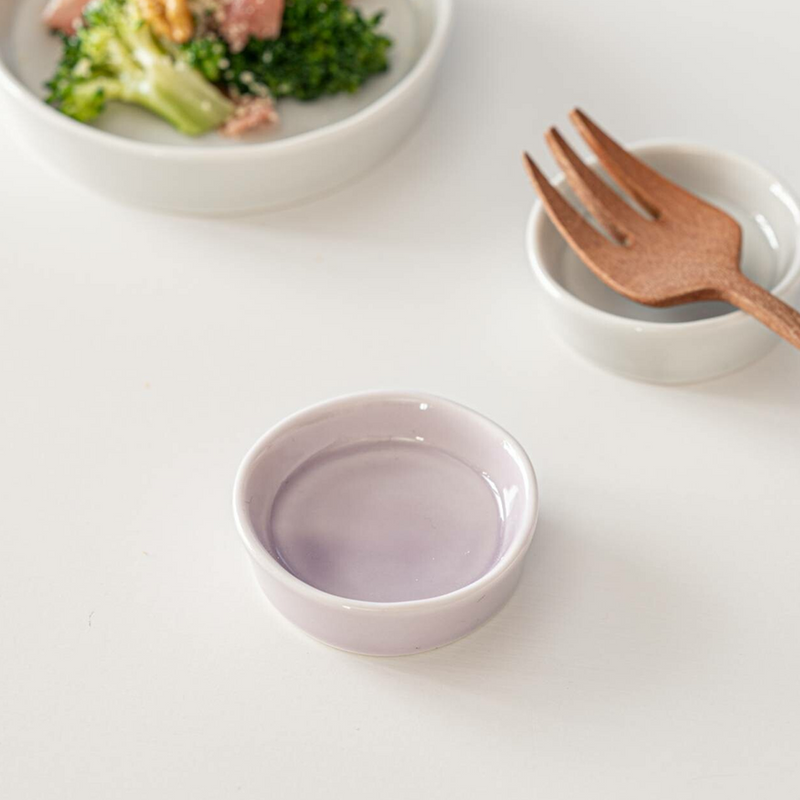 Miyama Luonto Cutlery Rest in Kaamos Purple pale lavender glaze, shown on a white surface alongside a white cutlery rest holding a wooden fork and a salad bowl in the background
