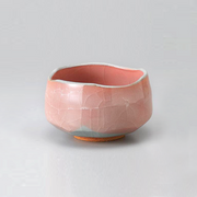 The Momoyama Red Crackle matcha bowl (chawan), featuring a vibrant reddish-pink crackle glaze, an irregular rim, and a partially unglazed foot, shown against a light grey background.
