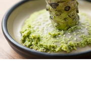 Close-up of ginger placed on a ceramic grater with finely grated ginger around the centre.

