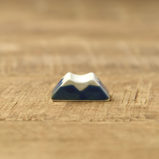 Ceramic Mount Fuji chopstick rest in deep navy blue with a white snow-capped peak, shown on a wooden surface
