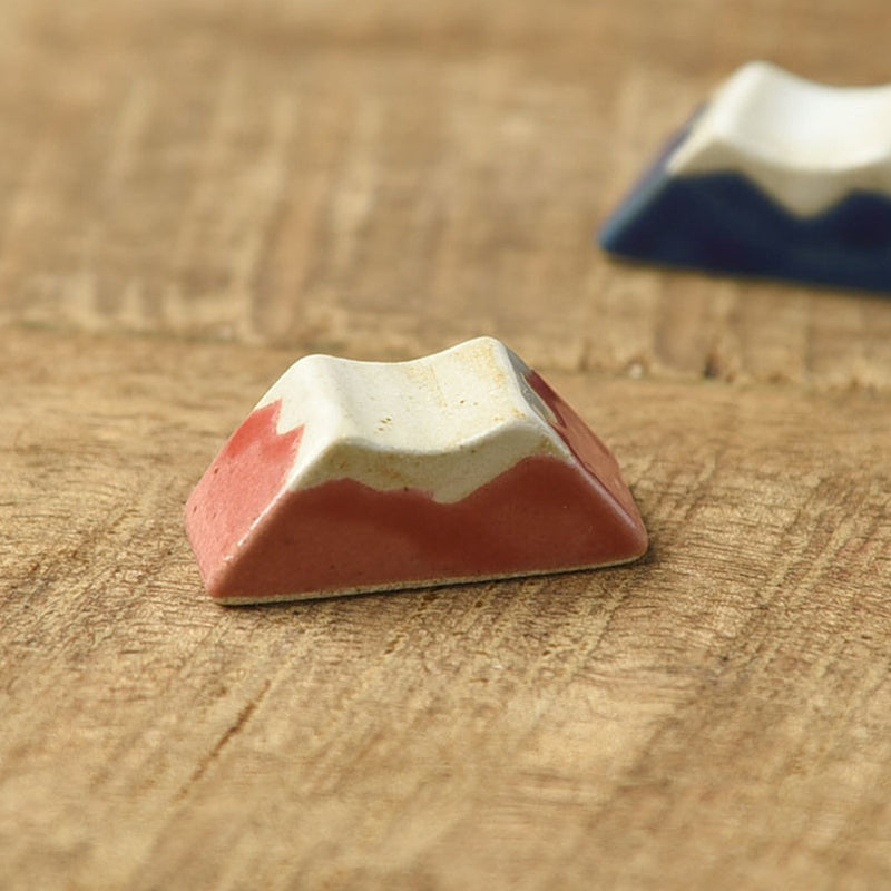 Red Mount Fuji chopstick rest in front of the blue version on a wooden table