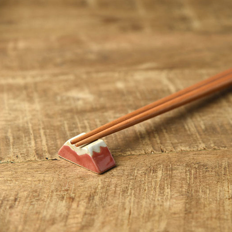 Wooden chopsticks resting on the red Mount Fuji chopstick rest