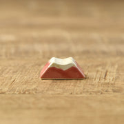 Oda Pottery Mount Fuji chopstick rest in red with a white snow-capped peak, on a wooden table