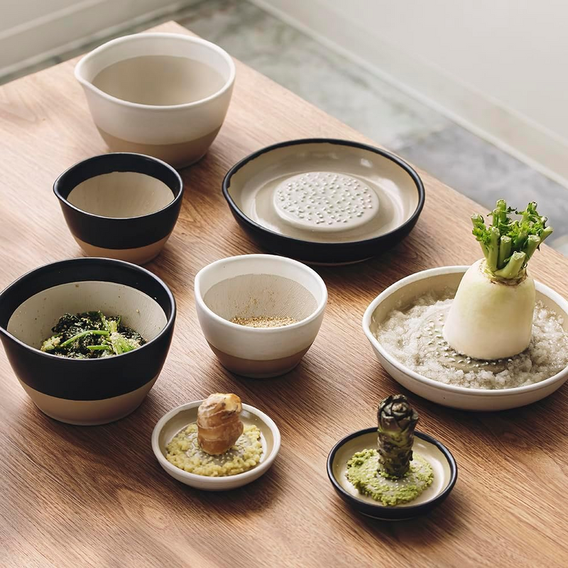 Set of small ceramic dishes with various food items on a wooden table