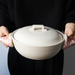 Close-up of hands using the pink checkered &NE pot holder to grip the lid of a large white ceramic pot, emphasizing the pot holder's functionality and stylish design.