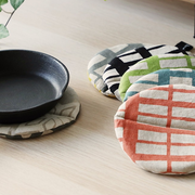 Collection of colourful round pot holders under cast iron cookware on a wooden surface.

