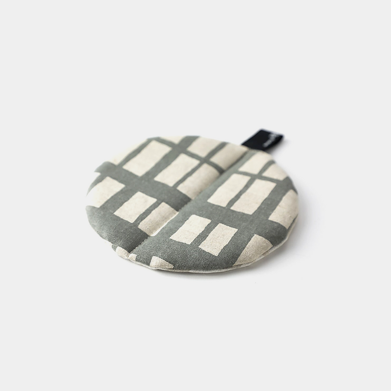The &NE Manmaru Pot Holder and Table Mat, a round, flat fabric trivet with a modern grey and white pattern.



