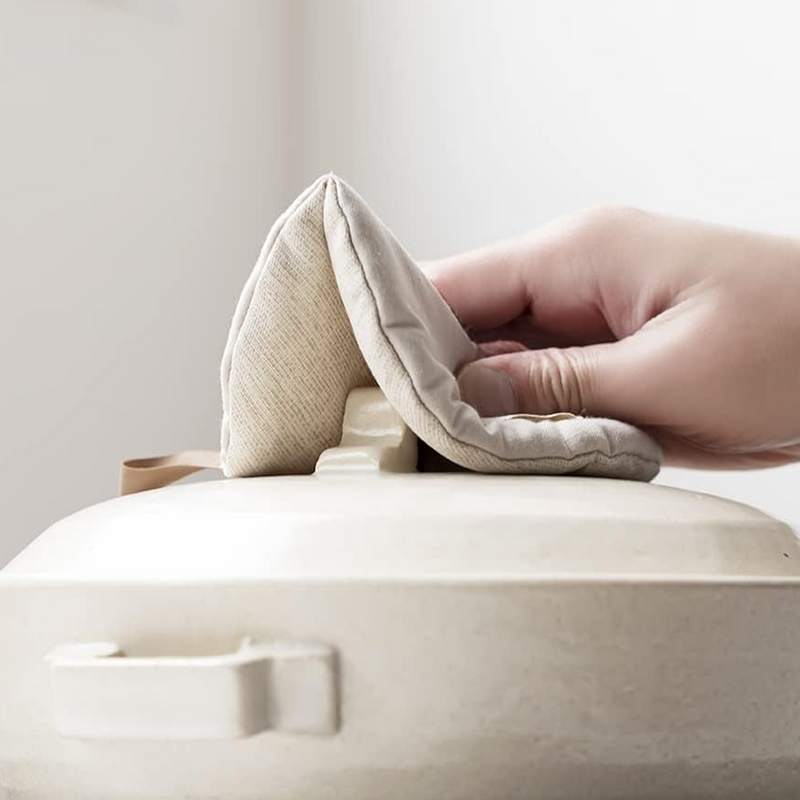 A flat lay of the round &NE Manmaru Pot Holder in Natural Beige, showing the central stitching line, logo tag, and hanging loop.