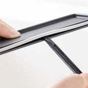 A person using the scraper end of the &NE Nikii cleaning brush to remove residue from a narrow groove in a container lid.